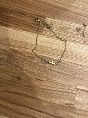 Guldfärgat armband med bokstav F