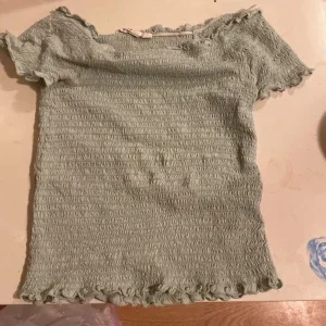 Ljusgrön smockad topp med volang