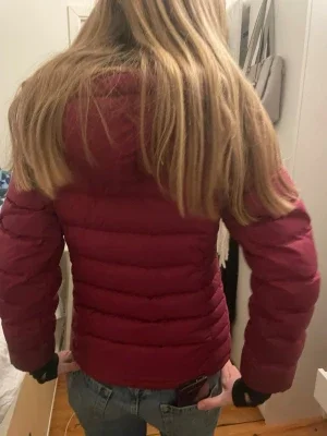 Vinröd dunjacka från bergans bra för skidåkning