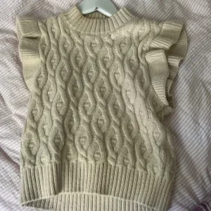 Beige stickad väst med volang från Name It