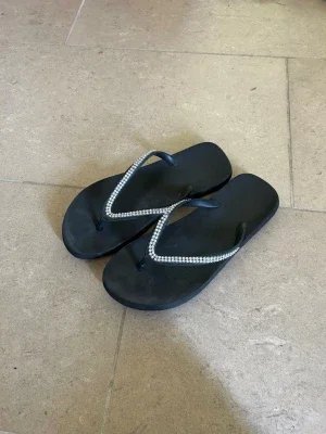 Svarta flip-flops med strassdetaljer