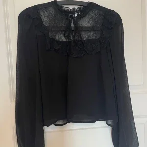Svart blus med spets och volang