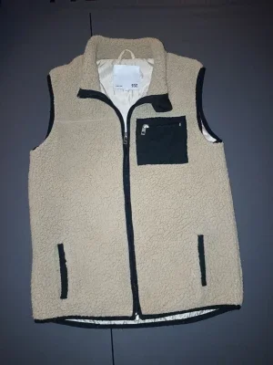 Beige fleeceväst med svarta detaljer