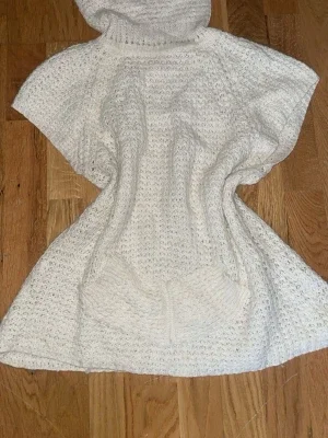 Vit stickad poncho med polokrage