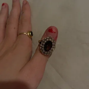 Guldfärgad ring med stor mörk sten