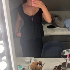 Svart blus med volang och knyt