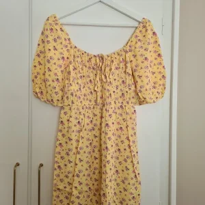 Gul blommig klänning med puffärm från Bikbok