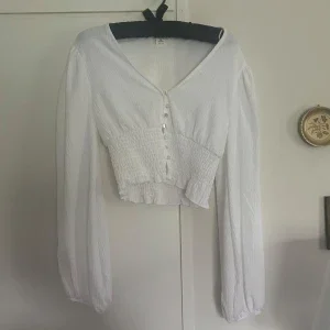 Vit blus med pärlemorknappar