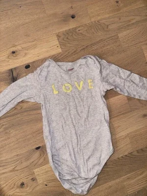 Grå body med LOVE-tryck från Livly Livly grå body, storlek 62/68