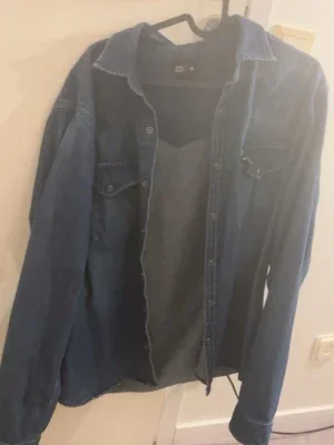 Blå jeansskjorta med knappar