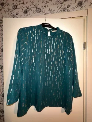 Grön blus med metallicdetaljer