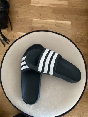 Svarta Adidas badtofflor med vita ränder