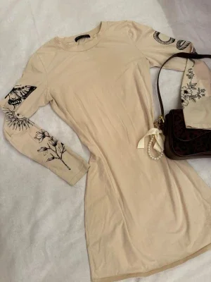 Beige långärmad klänning med tryck