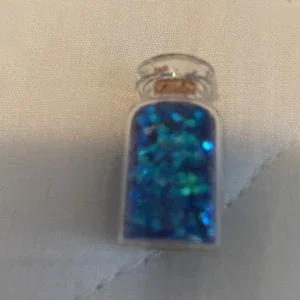 Litet glasflaska med blått glitter