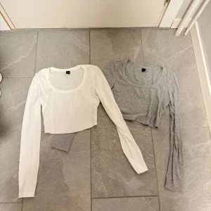 Två croppade långärmade toppar i vitt och grått