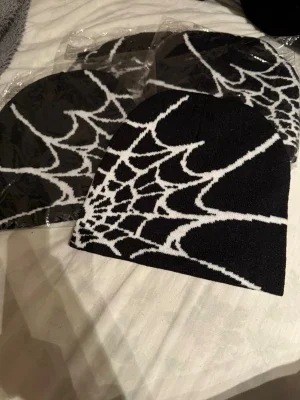 Svart mössa med spindelnätsmönster