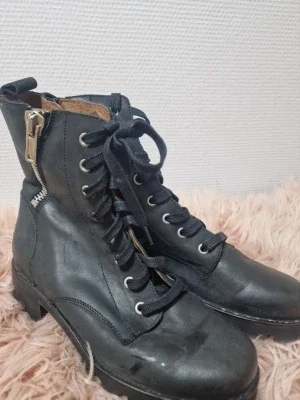 Svarta kängor med snörning och dragkedja
