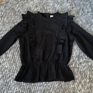 Svart blus med volangdetaljer