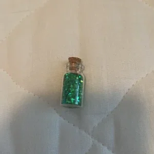 Litet glasflaska med grönt glitter