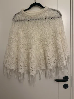 Vit stickad poncho från KappAhl