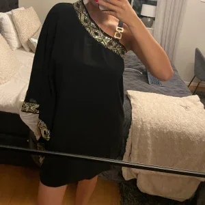 Svart one shoulder klänning med gulddetaljer