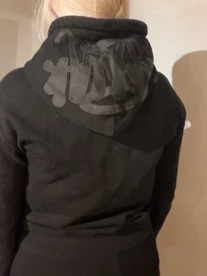 Svart märkes hoodie med tryck på huvan