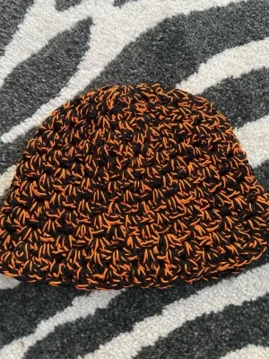Handvirkad svart och orange mössa