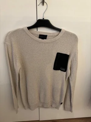 Beige stickad tröja med svart ficka