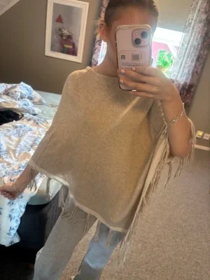 Beige poncho med fransar