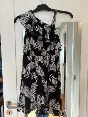 Svart one shoulder klänning med volang