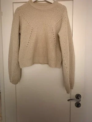 Beige stickad tröja med vida ärmar