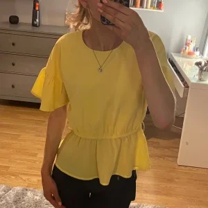 Gul blus med volangdetaljer