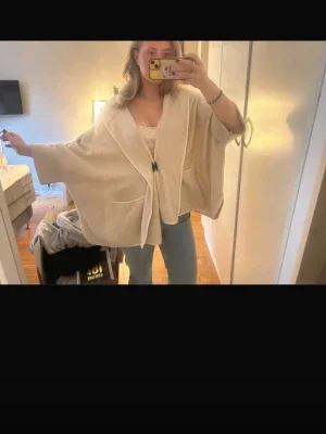 Beige poncho med knappar